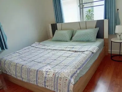 Cozy bedroom with wooden flooring and large window for natural light
