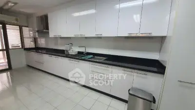 Spacious modern kitchen with sleek white cabinets and black countertops