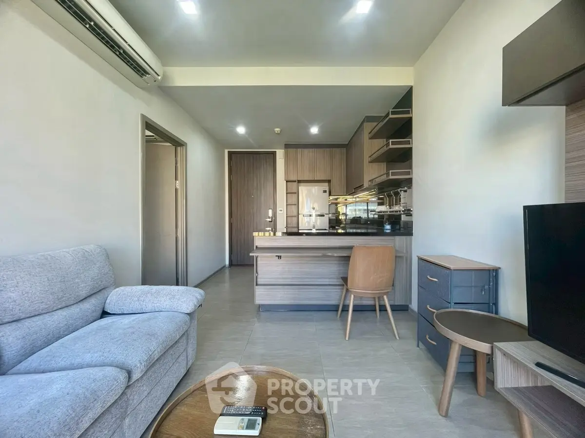 Modern living room with open kitchen, featuring sleek furniture and contemporary design.