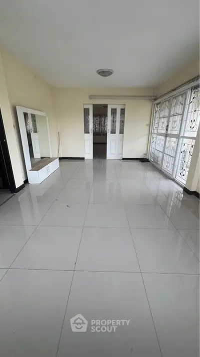 Spacious empty room with large windows and tiled flooring, ideal for customization.