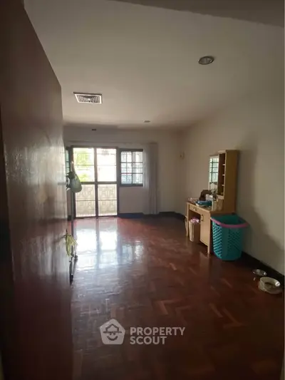 Spacious room with wooden flooring and natural light, ideal for versatile living space.