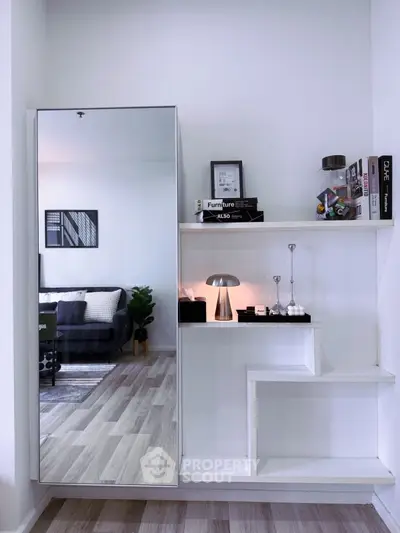 Modern living room with stylish shelving and mirror reflecting cozy sofa area.