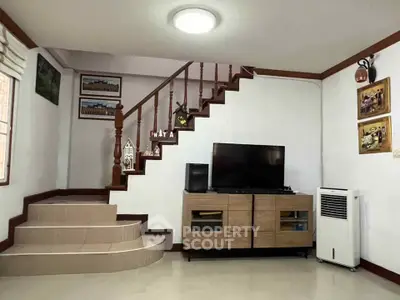 Cozy living room with modern TV setup and stylish staircase