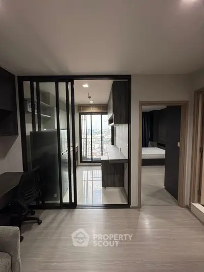 Modern apartment interior with open kitchen and study area, featuring sleek design and city view.