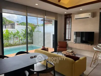 Luxurious living room with pool view, modern furniture, and large windows in a stylish home.