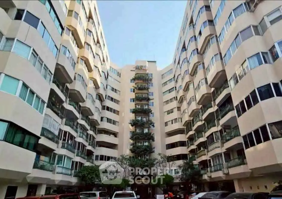 Stunning view of modern apartment building with unique architecture and ample parking space.