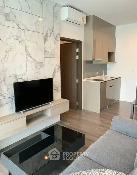 Modern living room with sleek kitchen, marble accent wall, and stylish furniture in a contemporary apartment.