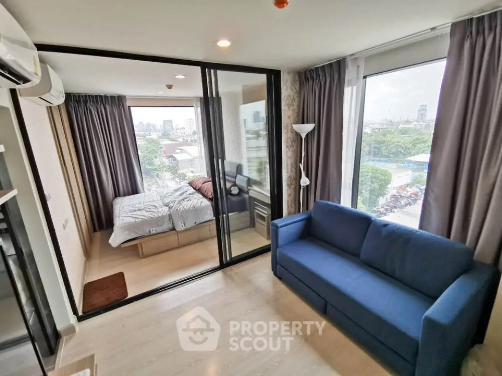 Modern apartment with glass-walled bedroom and city view, featuring a cozy living area and stylish decor.