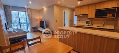 Modern open-plan living room and kitchen with city view balcony in luxury apartment.