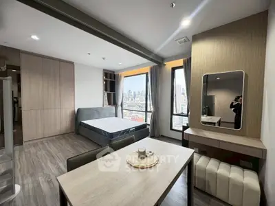 Modern studio apartment with city view, featuring sleek furniture and large windows.