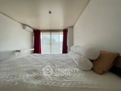 Spacious bedroom with large window and cozy bedding, offering a serene and inviting atmosphere.