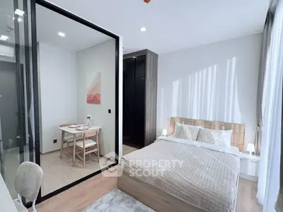 Modern bedroom with elegant decor and adjacent study area, featuring natural light and stylish furnishings.