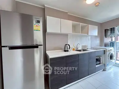 Modern kitchen with sleek cabinets, fridge, and washing machine in a stylish apartment.