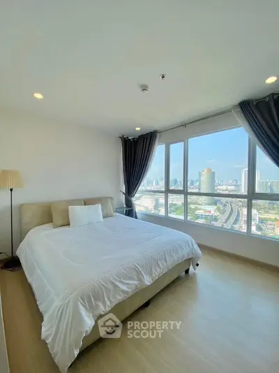 Spacious bedroom with stunning city view and large windows in modern apartment.