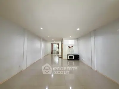 Spacious unfurnished living room with glossy tiled floors and recessed lighting