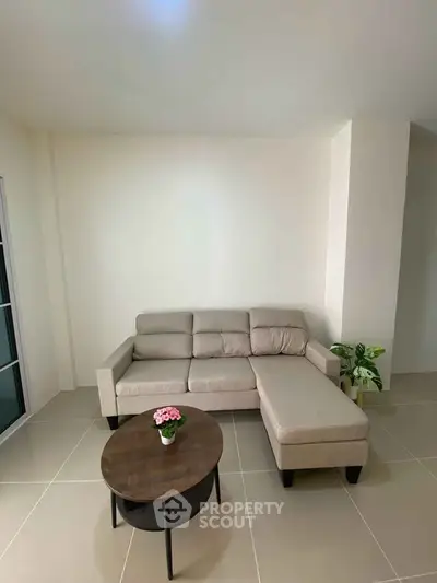 Modern living room with beige sectional sofa and round coffee table, perfect for cozy relaxation.