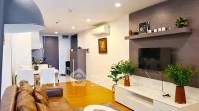 Modern living room with stylish decor and open dining area, featuring leather sofa and wall-mounted TV.