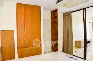 Spacious room with built-in wooden storage and sliding glass doors in modern apartment.