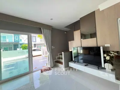 Modern living room with large TV and sliding glass doors leading to patio