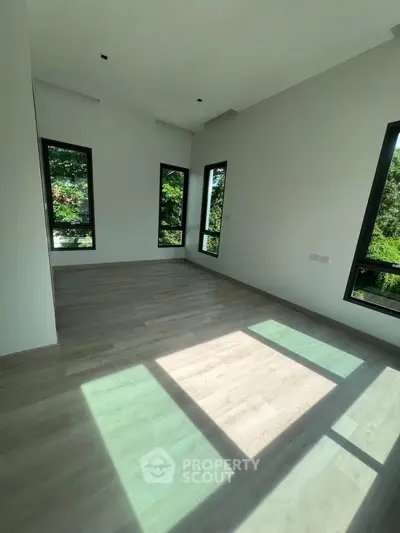 Spacious room with large windows and lush green views, perfect for a serene living space.