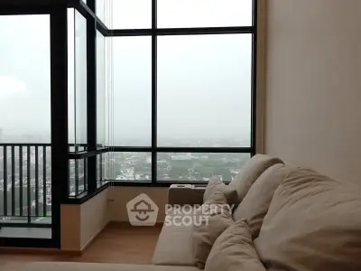 Spacious living room with large windows offering a stunning city view, featuring cozy beige sofas.