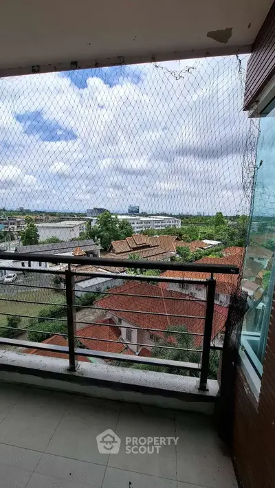 Spacious balcony with safety netting offering panoramic views of the city skyline and lush greenery.