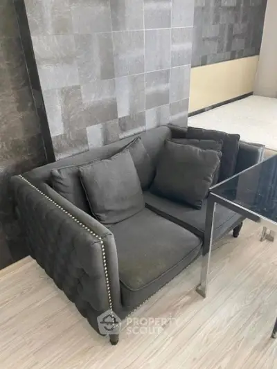 Modern living room with stylish dark sofa and sleek glass table on light wood flooring.