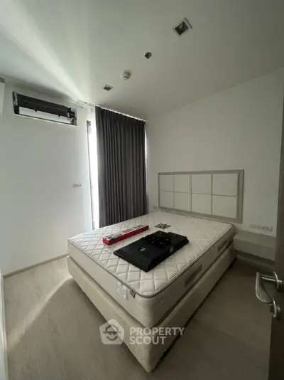 Modern bedroom with natural light, featuring a comfortable mattress and sleek design elements.