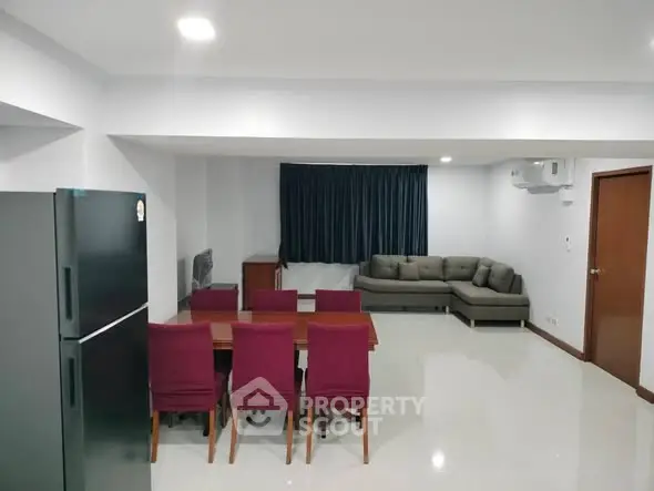 Spacious living room with modern furniture and dining area in open layout apartment.