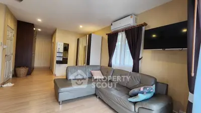 Spacious living room with modern leather sofa and wall-mounted TV