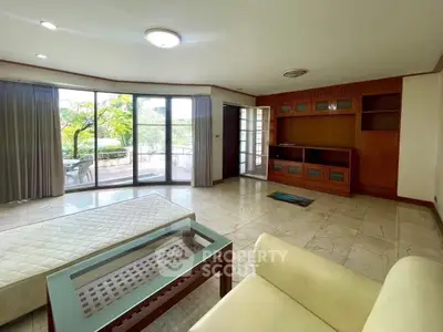 Spacious living room with large windows and garden view, featuring elegant furniture and natural light.