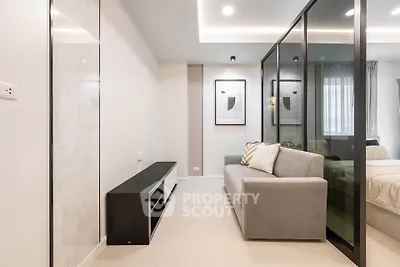 Modern living room with sleek design and glass partition, featuring a cozy sofa and stylish decor.