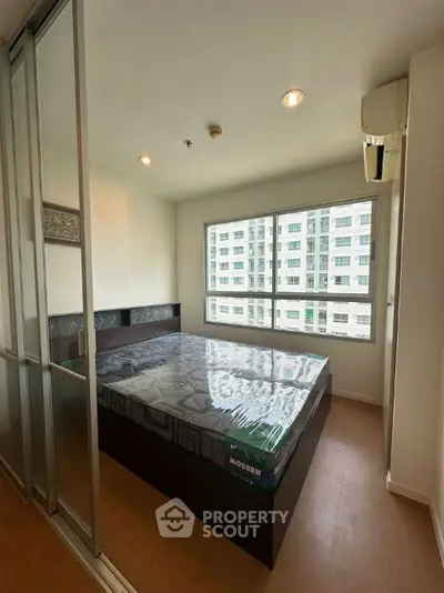 Modern bedroom with large windows and sleek design in urban apartment.