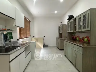 Spacious kitchen with modern cabinetry and ample natural light, perfect for culinary enthusiasts.