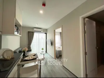 Modern apartment interior with open kitchen and cozy living area leading to a bright bedroom.