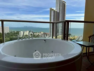 Luxurious balcony with jacuzzi offering stunning ocean and city views in high-rise apartment.