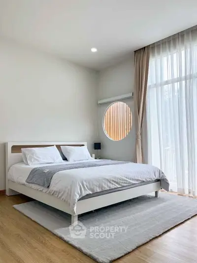 Modern bedroom with stylish decor and large window for natural light.