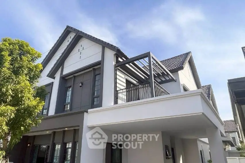 Modern two-story house with stylish balcony and sloped roof design.