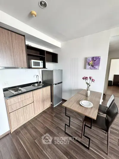 Modern kitchen with sleek cabinetry, compact dining area, and stylish decor in a cozy apartment setting.