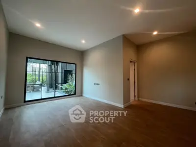 Spacious modern living room with large window overlooking a garden patio.