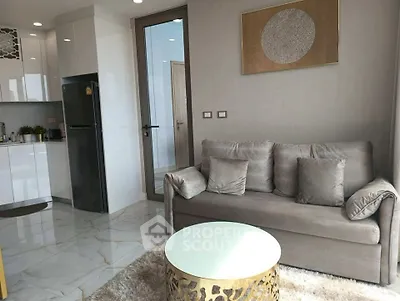 Modern living room with elegant decor and open kitchen layout, featuring a cozy sofa and stylish coffee table.
