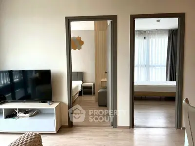 Modern apartment interior with two bedrooms and a living area featuring a TV and natural light.