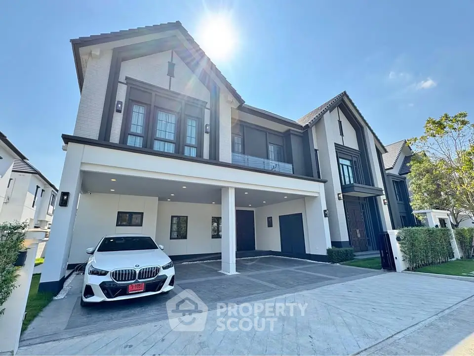 Luxurious modern house with spacious driveway and sleek car parked, under clear blue sky.