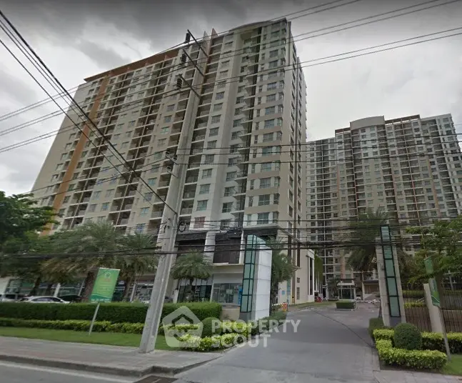 Modern high-rise residential building with lush landscaping and secure entrance.