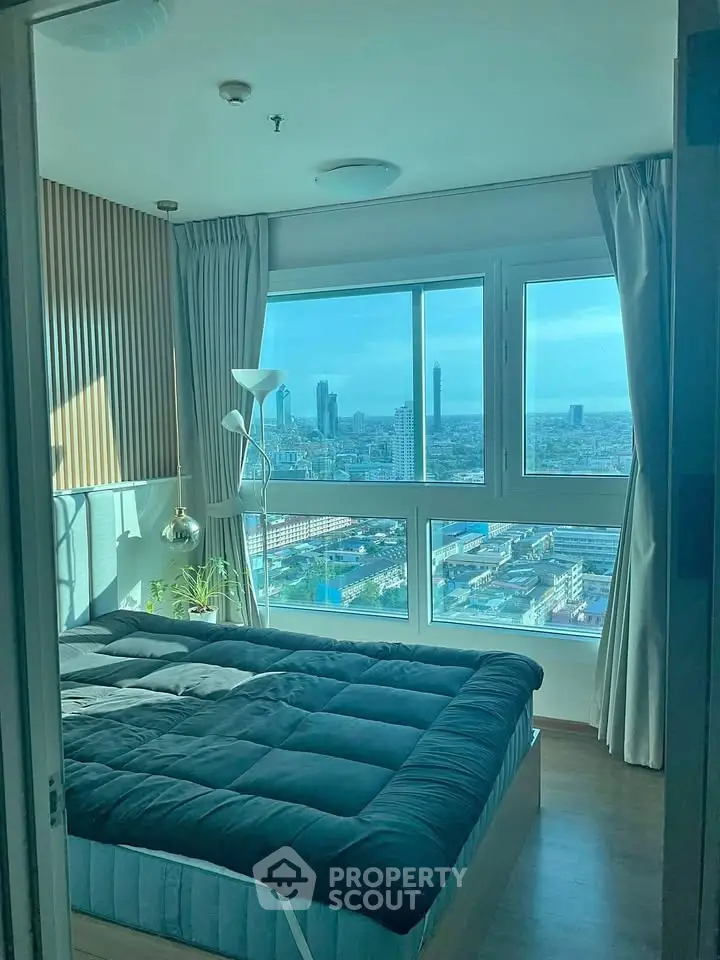 Modern bedroom with stunning city view through large windows, featuring cozy bedding and stylish decor.