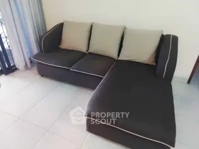 Spacious living room with modern L-shaped sofa and elegant curtains.