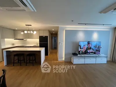 Modern open-plan living room with stylish kitchen and large TV setup.