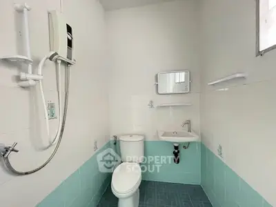Compact bathroom with modern fixtures and light blue tiles, featuring a shower and small sink.