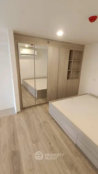 Modern bedroom with mirrored wardrobe and wooden flooring in a stylish apartment.