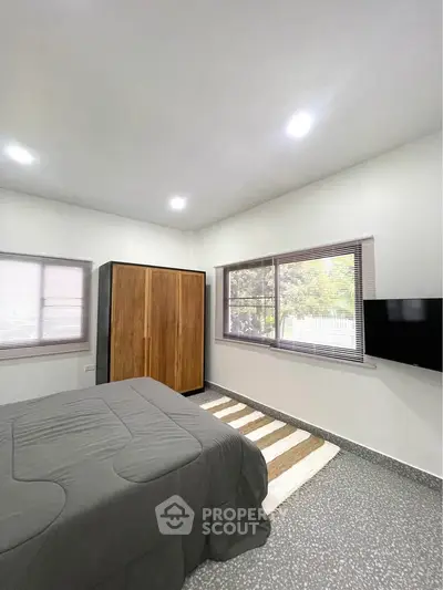 Spacious bedroom with large windows and modern wardrobe in a cozy home.